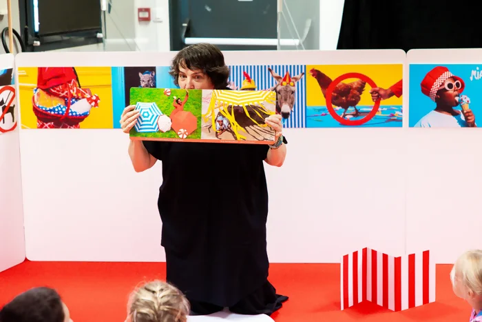 Photo de l'autrice-plasticienne photographe Claire Dé qui anime son atelier Qui veut jouer avec moi? en lisant l'album éponyme. L'animation se déroule dans son installation terrain de jeu.