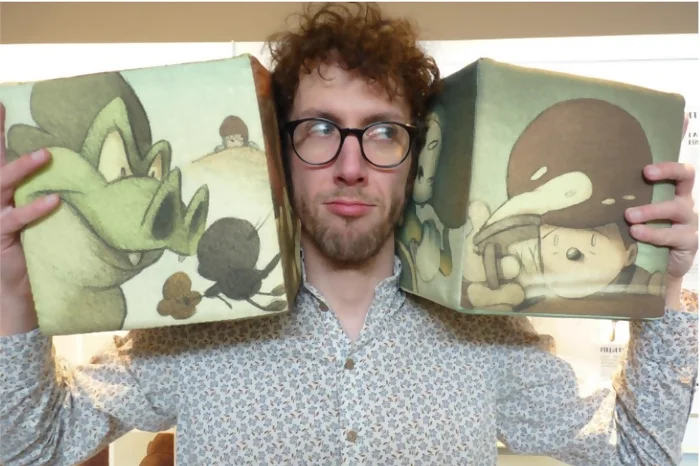 L'auteur David Périmony tie deux blocs de l'activité cubes Billy Symphony entre ses mains. Les blocs encadrent sa tête.