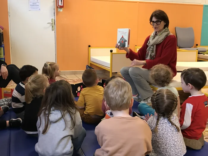 Laure Montaigne, médiatrice chez Perluette, en train de lire un album devant des maternelles.