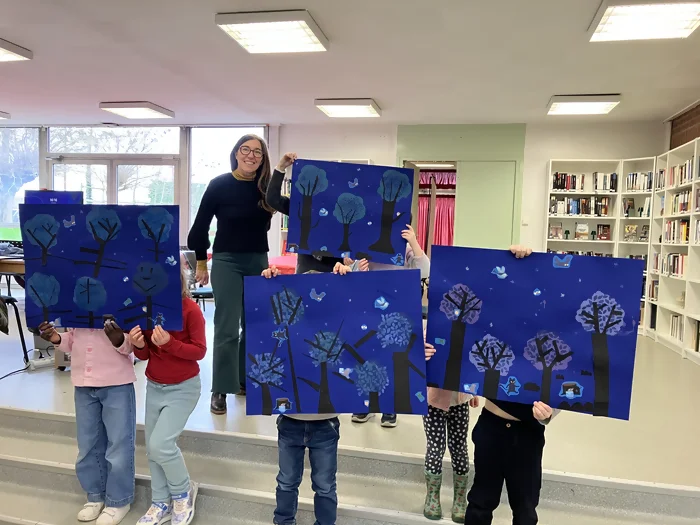 On voit les enfants et Delphine Chedru. Les jeunes tiennent devant eux les tableaux qu'ils ont réaliser sur le livre "la lettre de minuit".