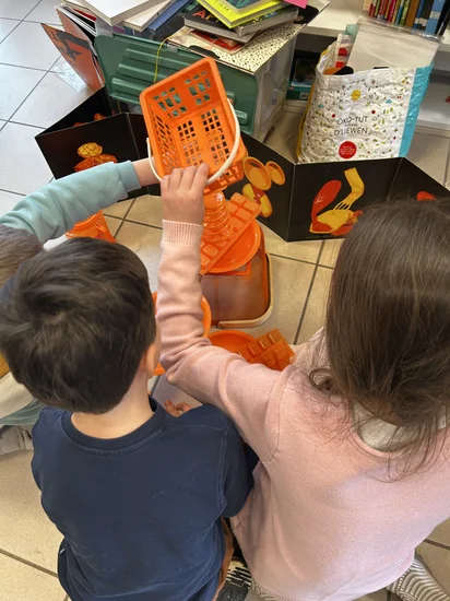 Des enfants en train de jouer à faire des constructions avec de la vaisselle en plastique avec comme inspiration un album de Claire Dé : "À toi de jouer !" (Éditions Les Grandes Personnes).