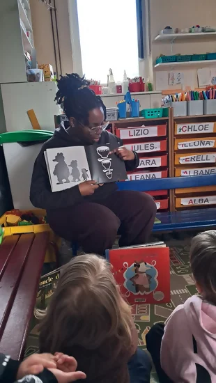 Célia, jeune en service civique à Perluette dans l'année 2026, en train de lire l'album "trois ours" dans une classe de maternelle à l'école Salengro à Orchies.