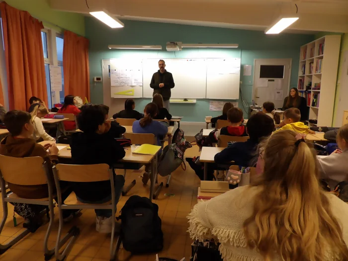 On voit l'auteur Hervé Hernu dans une salle de classe de collège en train d'intervenir en présentation devant les élèves
