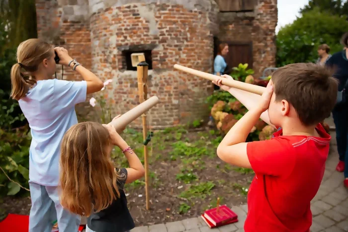 Photos de Trois jeunes en train de regarder les éléments de décoration autour de La Tour pendant les journées du Patrimoine. Ils observent dans des longues vues et jumelles en carton. Crédit photo : Kalimba.