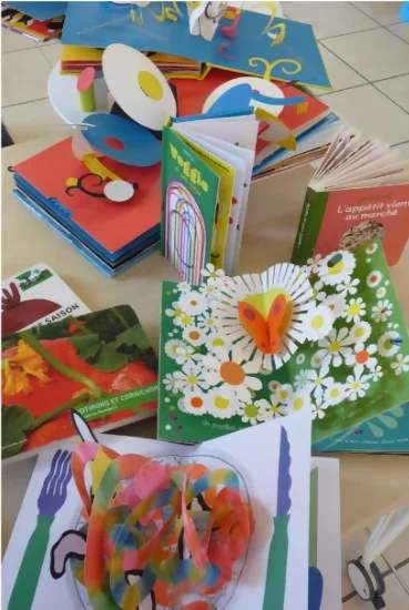 Un assemblage de livres pop-up, ouverts. On peut voir "action", "veggies", "papillons", "l'appétit vient en mangeant" et d'autres encore. C'est très coloré et joyeux