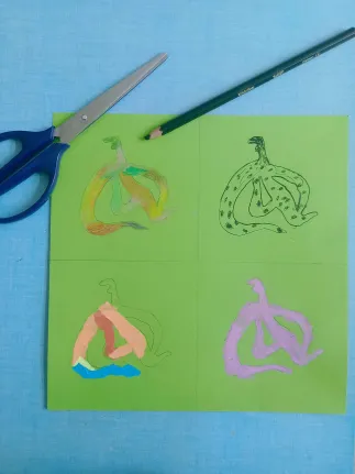 On voit quatre bananes sur une feuille de papier verte. Elles sont faits avec des techniques différentes (encre de chine, collage, aquarelle et craies grasses). Des ciseaux etun crayon sont aussi présents sur l'image