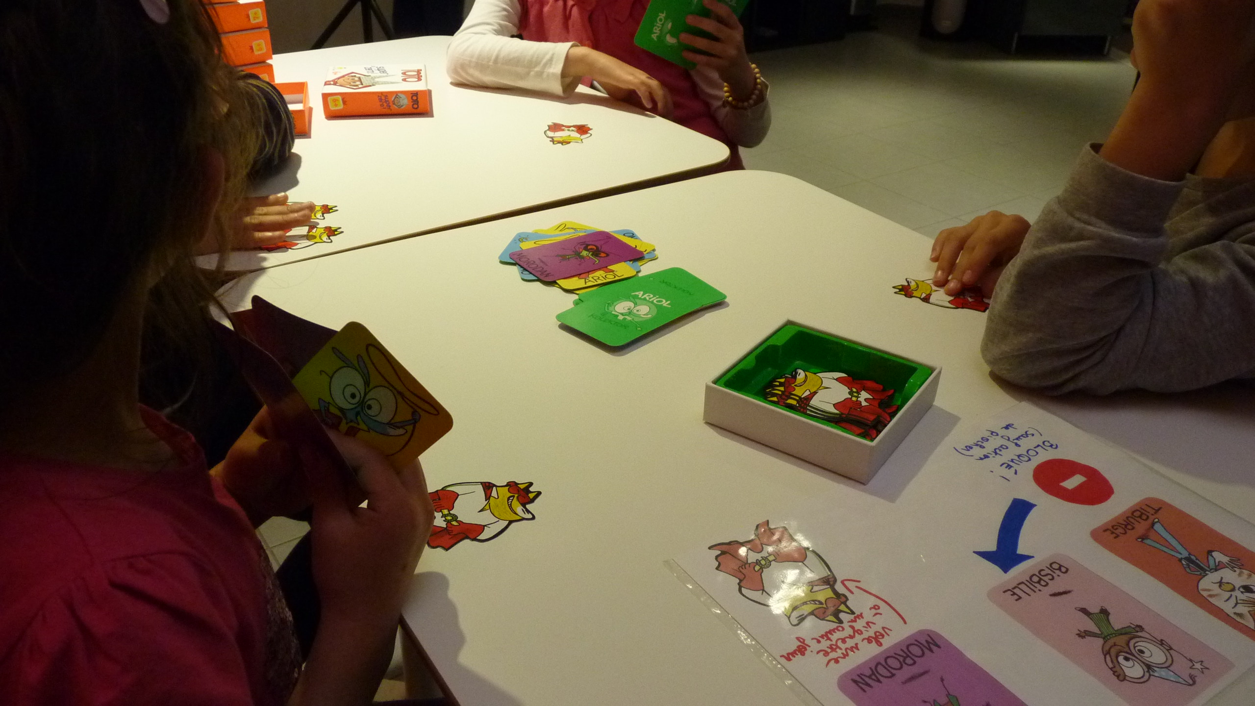 Des enfants autour d'une table jouent à un jeu de cartes "Ariol" (BD Bayard)