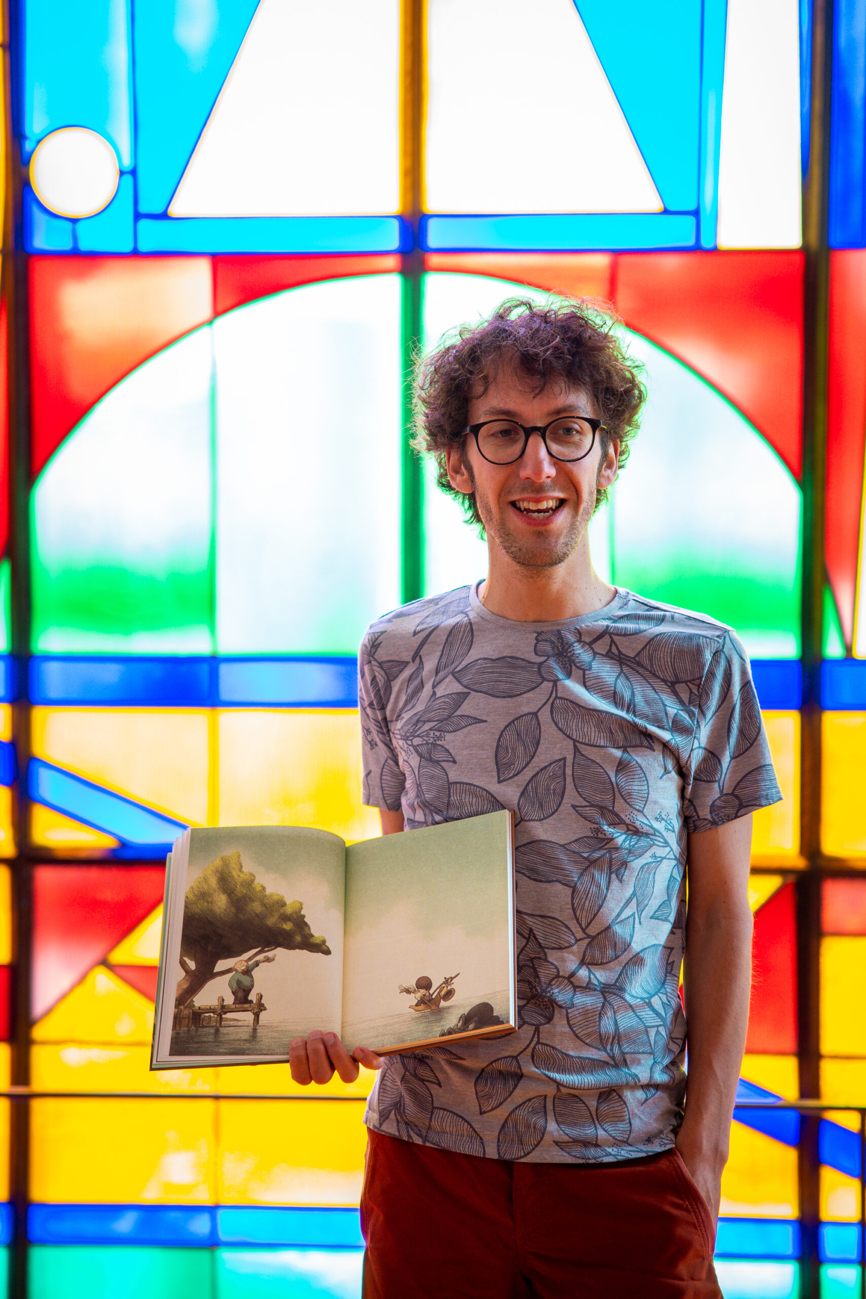 L'auteur David Périmony fait la lecture de son album Billy Symphony devant un vitrail aux couleurs éclatantes